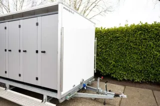 Grote toiletwagen DL1400 met meerdere deuren op een evenemententerrein