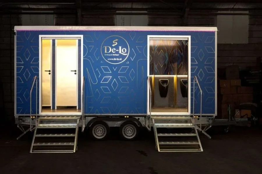 Luxe toiletwagen met verlichte deuren, opgesteld bij een feestlocatie